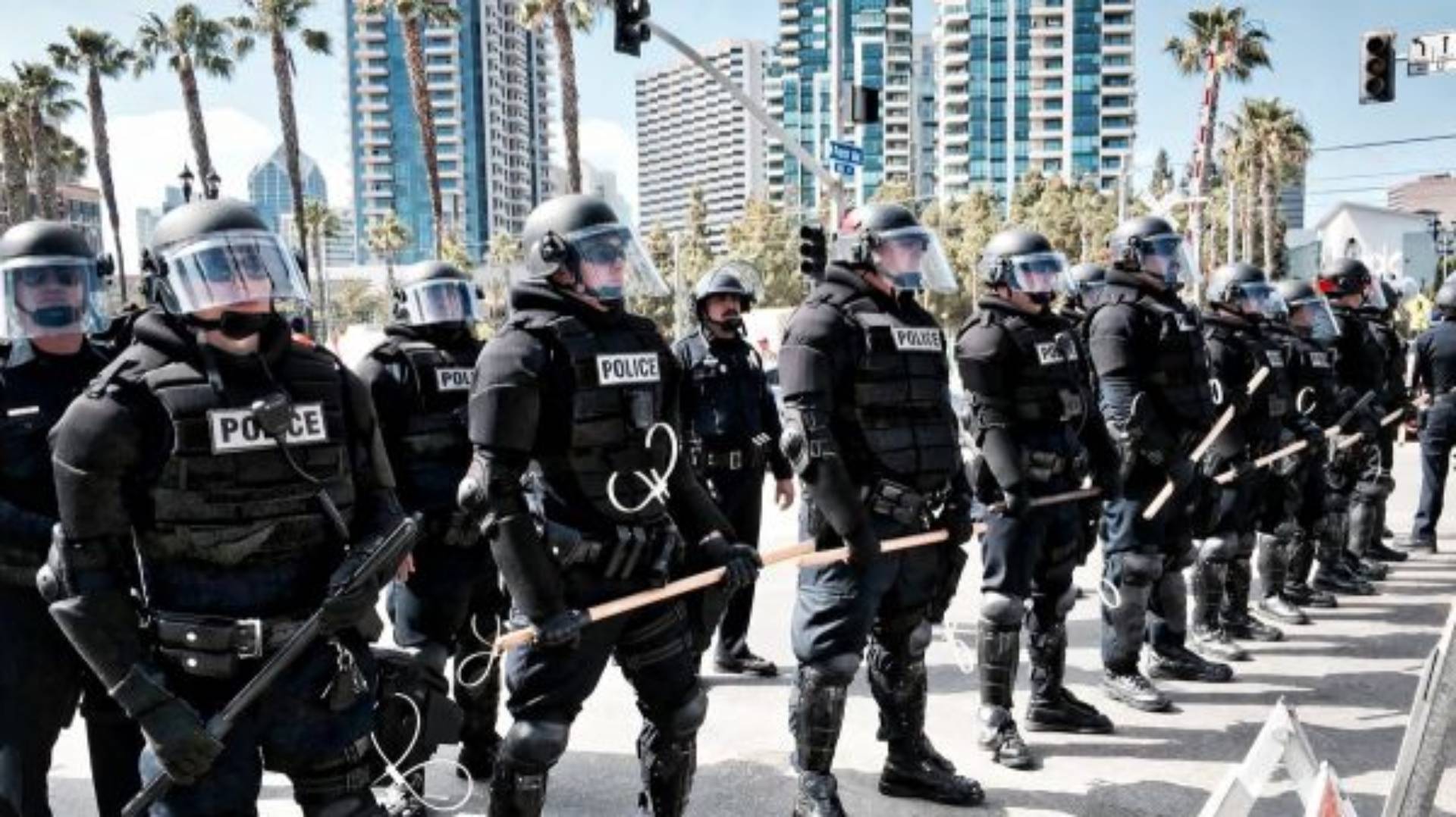 row of police in riot gear holding weapons